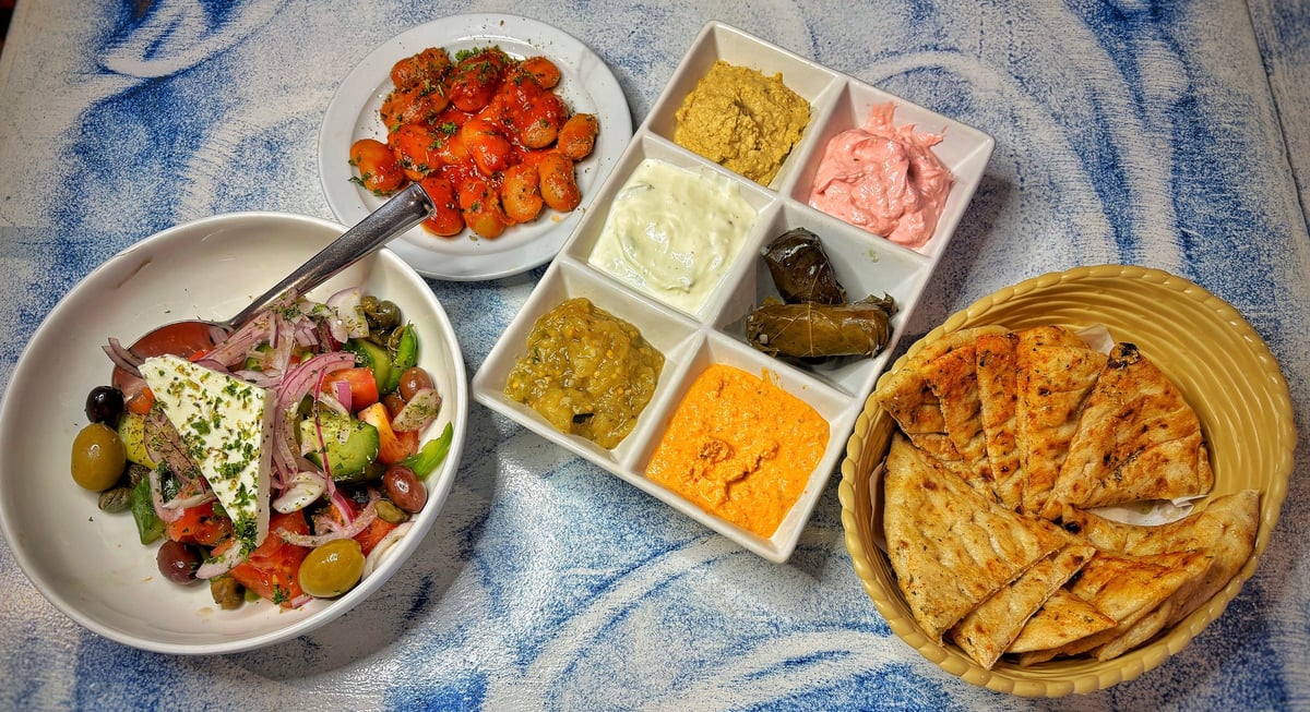 Round one of Zorba's meze — Greek salad, five dips with pitta bread and dolmadakia on a blue patterned tablecloth
